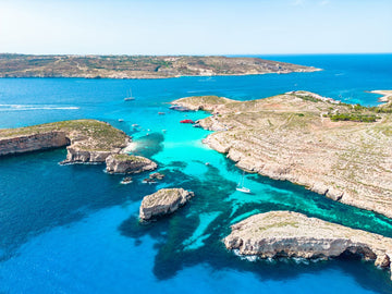 Turquoise Blue Lagoon in Comino Malta aerial view with crystal clear water and rocky coastline